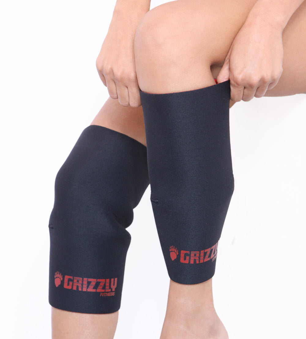 Person wearing black knee sleeves with Grizzly logo on a white background